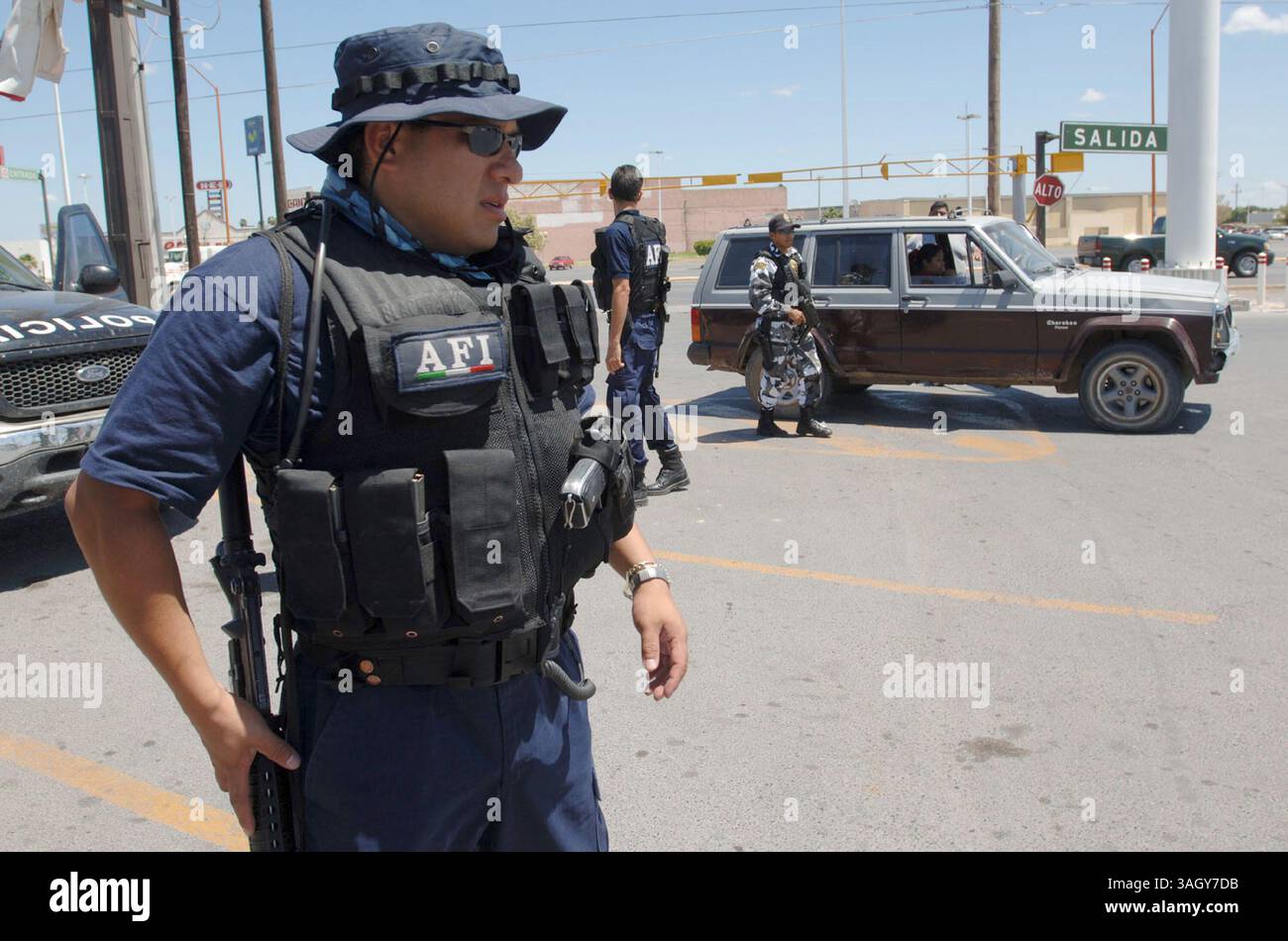 07 agosto 2005 - Nuevo Laredo, Tamaulipas, Messico - Un ufficiale pesantemente armato dell'Agenzia Federale d'inchiesta, l'equivalente messicano dell'FBI, fa la guardia mentre gli agenti federali perlustrano un'auto che gestiva un blocco stradale di polizia a Nuevo Laredo, Messico. (Immagine di credito: © Luis J. Jimenez/ZUMA Press) Foto Stock