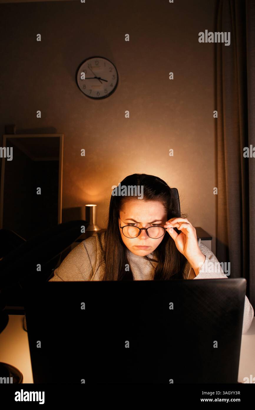 Una donna che lavora sodo lavora al computer nel suo ufficio domestico e cerca di risolvere i problemi di lavoro. Sentimento di disperazione e bruciati per problemi di lavoro Foto Stock