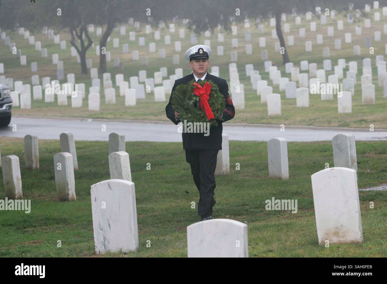 12 dicembre 2009 - San Diego, California, Messico - 12 dicembre 2009,- San Diego, CA,- 100 corone sono state posizionate al ft. Rosecrans National Cemetery come parte del programma Wreath Across America. Diverse organizzazioni locali e rami dell'esercito sono stati rappresentati durante la cerimonia che è stata abbreviata con la pioggia. Il sottufficiale dell'USN Jesus Lozoya portò una corona da collocare su una tomba nel cimitero. (John Gibbins/Union-Tribune) foto obbligatoria Credit:JOHN GIBBINS/Union-Tribune/ZUMA press (immagine di credito: © The San Diego Union-Tribune/ZUMApress.com) Foto Stock