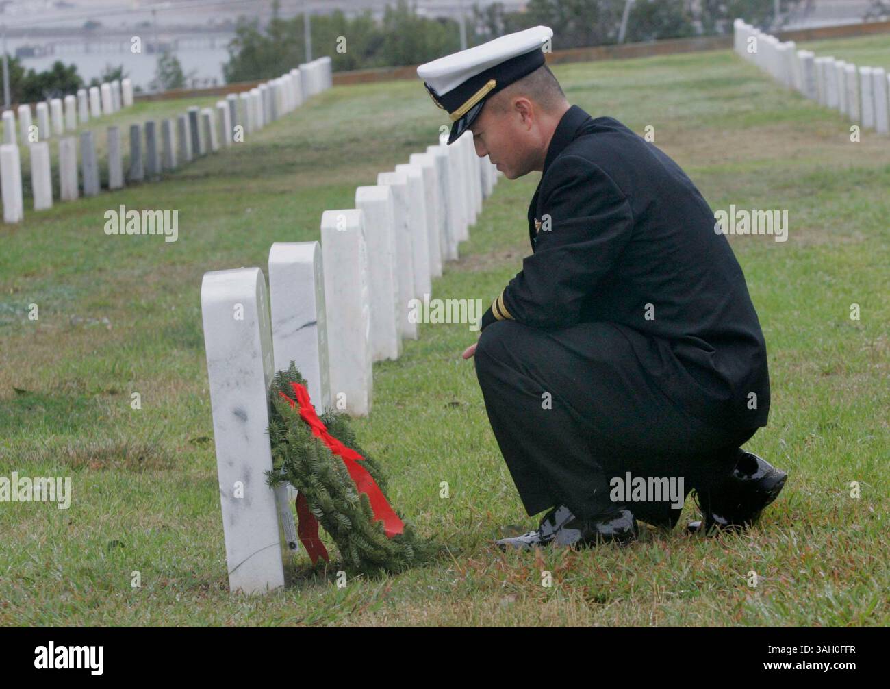 12 dicembre 2009 - San Diego, California, Messico - 12 dicembre 2009,- San Diego, CA,- 100 corone sono state posizionate al ft. Rosecrans National Cemetery come parte del programma Wreath Across America. Diverse organizzazioni locali e rami dell'esercito sono stati rappresentati durante la cerimonia che è stata abbreviata con la pioggia. Il cappellano della Marina, il tenente Song Huang, pose una corona di fronte alla tomba di un soldato al cimitero. (John Gibbins/Union-Tribune) foto obbligatoria Credit:JOHN GIBBINS/Union-Tribune/ZUMA press (immagine di credito: © The San Diego Union-Tribune/ZUMApress.com) Foto Stock