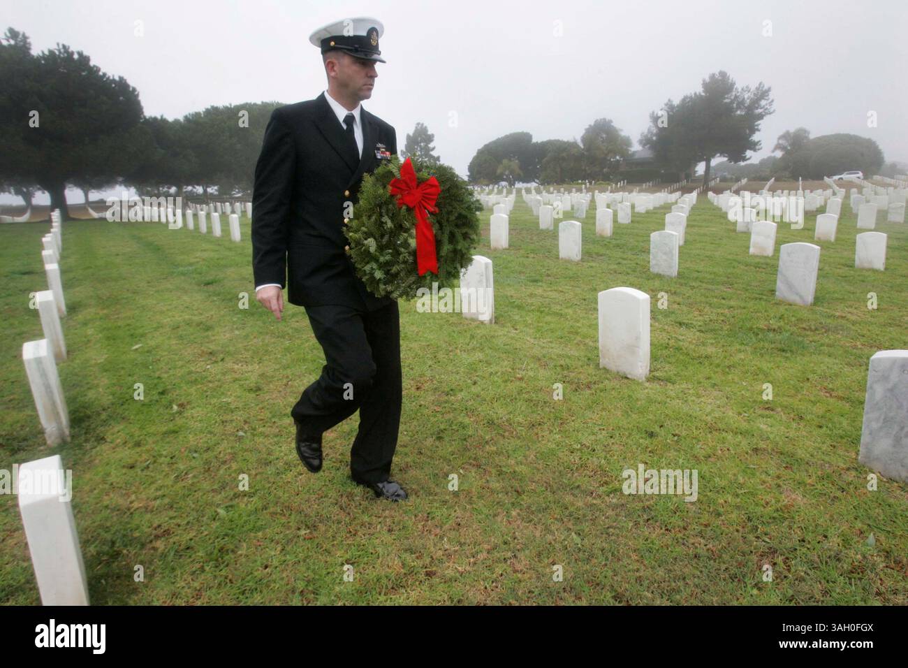12 dicembre 2009 - San Diego, California, Messico - 12 dicembre 2009,- San Diego, CA,- 100 corone sono state posizionate al ft. Rosecrans National Cemetery come parte del programma Wreath Across America. Diverse organizzazioni locali e rami dell'esercito sono stati rappresentati durante la cerimonia che è stata abbreviata con la pioggia. Il sottufficiale della USN Alfred Dougherty portò una corona da collocare su una delle tombe del cimitero. (John Gibbins/Union-Tribune) foto obbligatoria Credit:JOHN GIBBINS/Union-Tribune/ZUMA press (immagine di credito: © The San Diego Union-Tribune/ZUMApress.com) Foto Stock