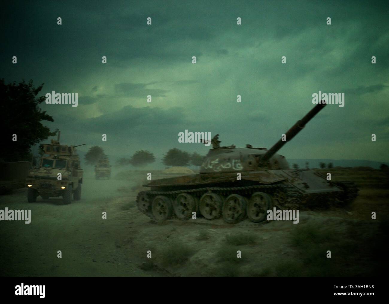 14 giugno 2009 - Jalalabad, Afghanistan - i veicoli MRAP (Mine-Resistant Ambush Protected) passano davanti a un carro armato russo distrutto lasciato sul lato della strada nella provincia di Nangahar. (Immagine di credito: © John Goodman/ZUMA Press) Foto Stock