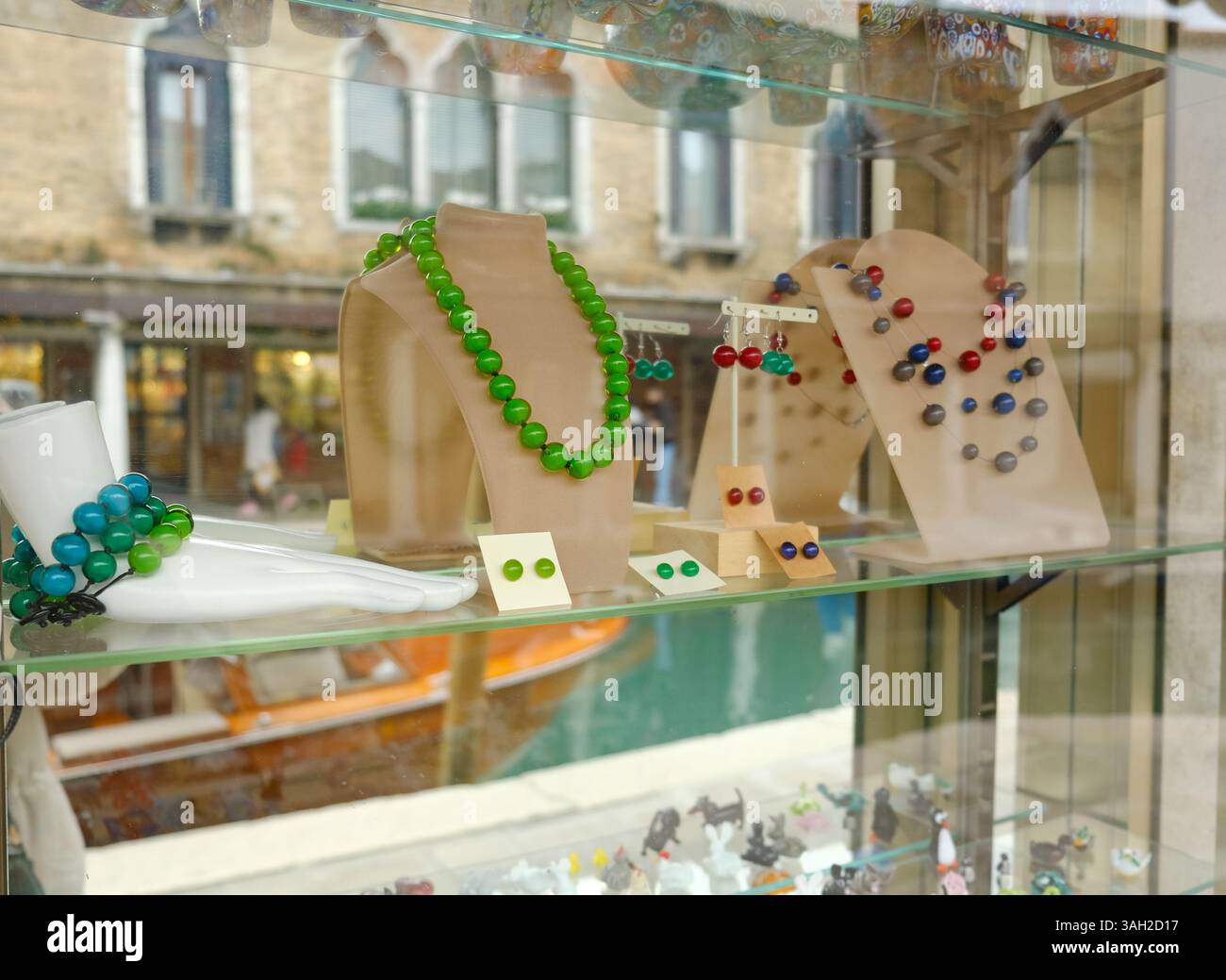 Vetrina di gioielli colorati in vetro di Murano in una vetrina. Include collana con perline verdi, orecchini e un bracciale con perline blu e verde. Foto Stock