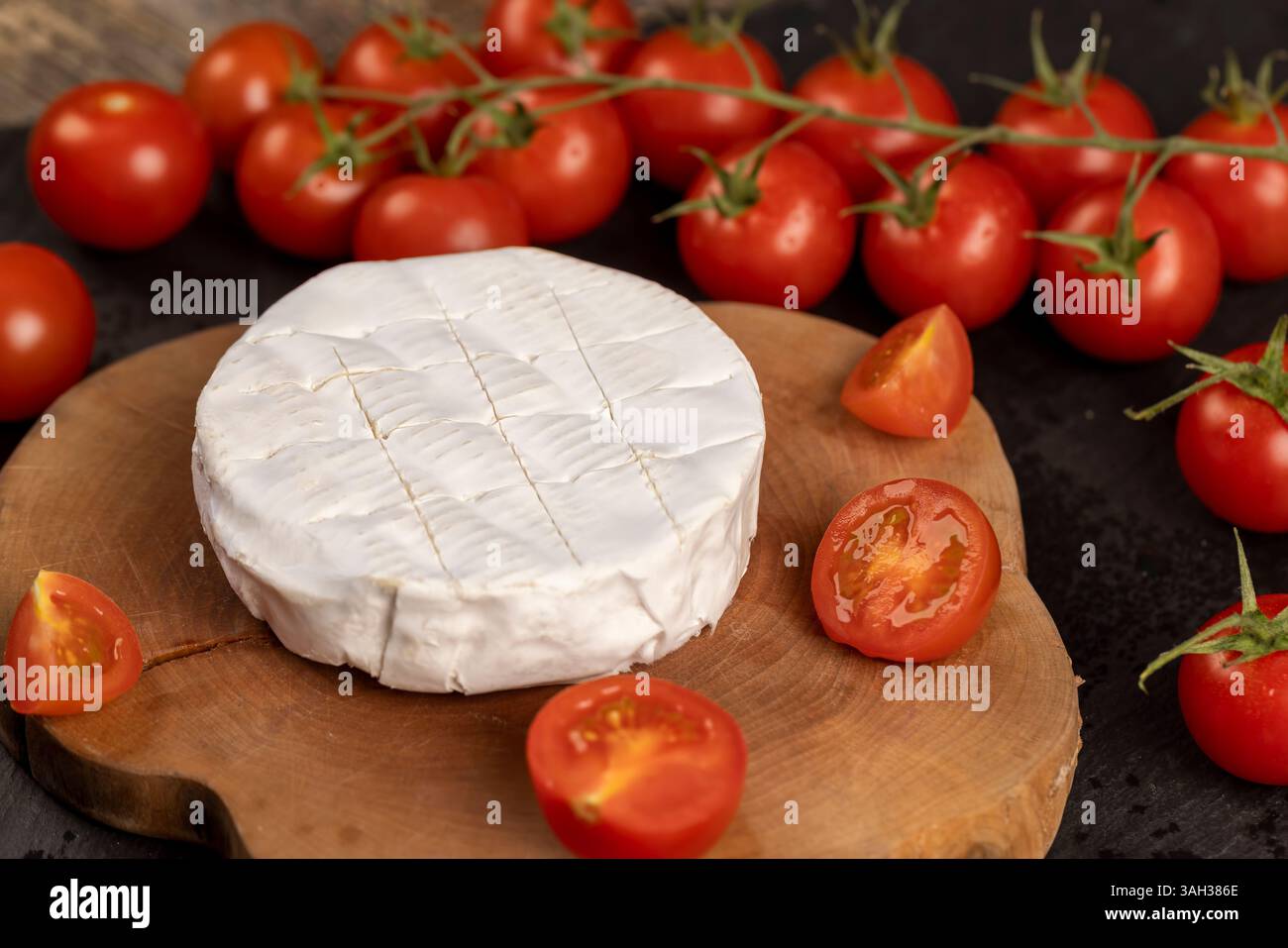 formaggio morbido con pomodori rossi maturi e muffa, un pezzo di formaggio morbido maturo e alcuni pomodori rotondi rossi sul tavolo, vista dall'alto, vista laterale Foto Stock
