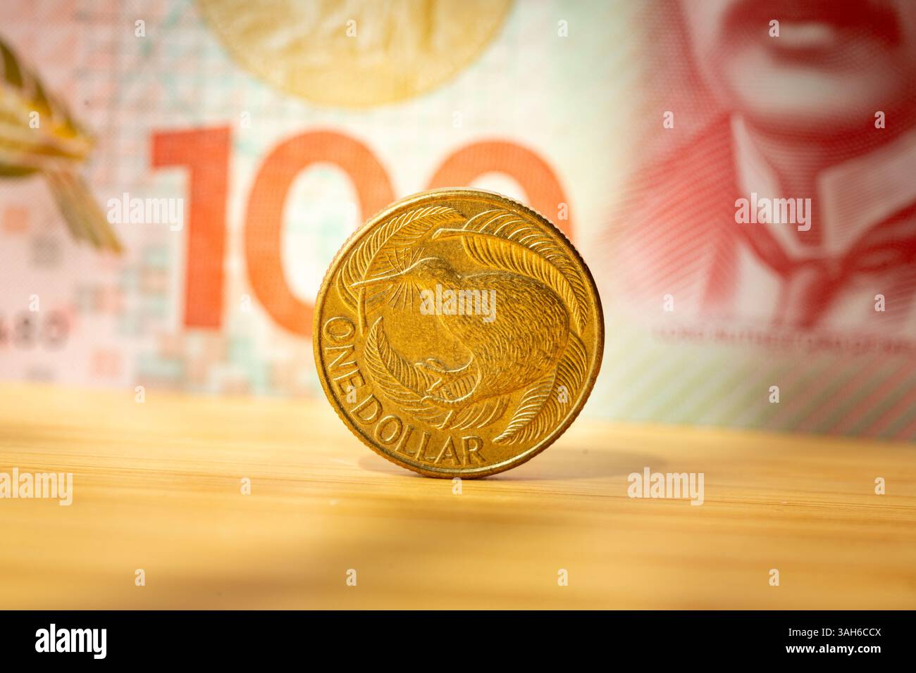 Moneta da un dollaro neozelandese su sfondo banconota da 100 dollari. Concetto finanziario Foto Stock