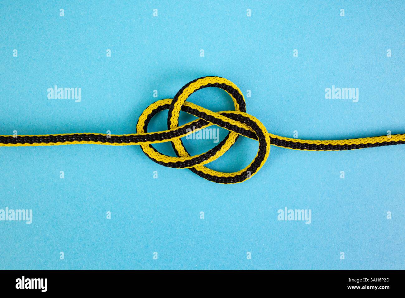 Il nodo marino sciolto del cordone sintetico viene spiegato su sfondo blu Foto Stock