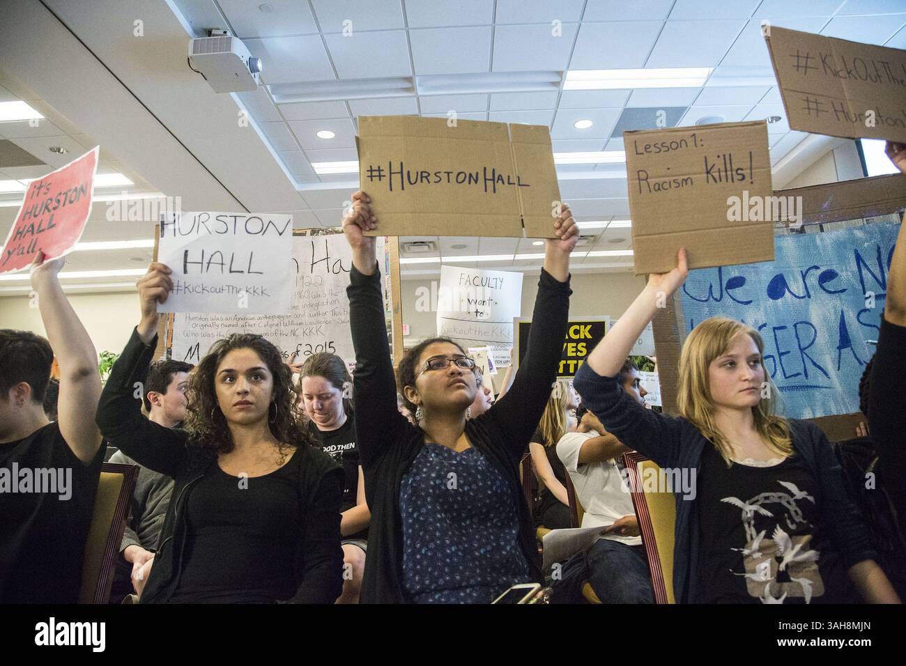 25 marzo 2015 - Chapel Hill, North Carolina, USA - dimostranti da sinistra, Jaslina Paintal. Anisha Padma e Danielle Allyn hanno dei segni mentre i fiduciari dell'UNC parlano da entrambi i lati della questione della ridenominazione e della ridefinizione dei punti di riferimento del campus UNC-Chapel Hill chiamati per i partecipanti alla guerra civile e i leader della supremazia bianca mercoledì 25 marzo 2015 al Rizzo Conference Center di Meadowmont a Chapel Hill, N.C. gli attivisti studenteschi hanno spinto i fiduciari di Chapel Hill per rinominare Saunders Hall, che onora il colonnello confederato e il leader del KKK William Saunders. Allo stesso modo, gli studenti vogliono mettere una targa accanto al si Foto Stock