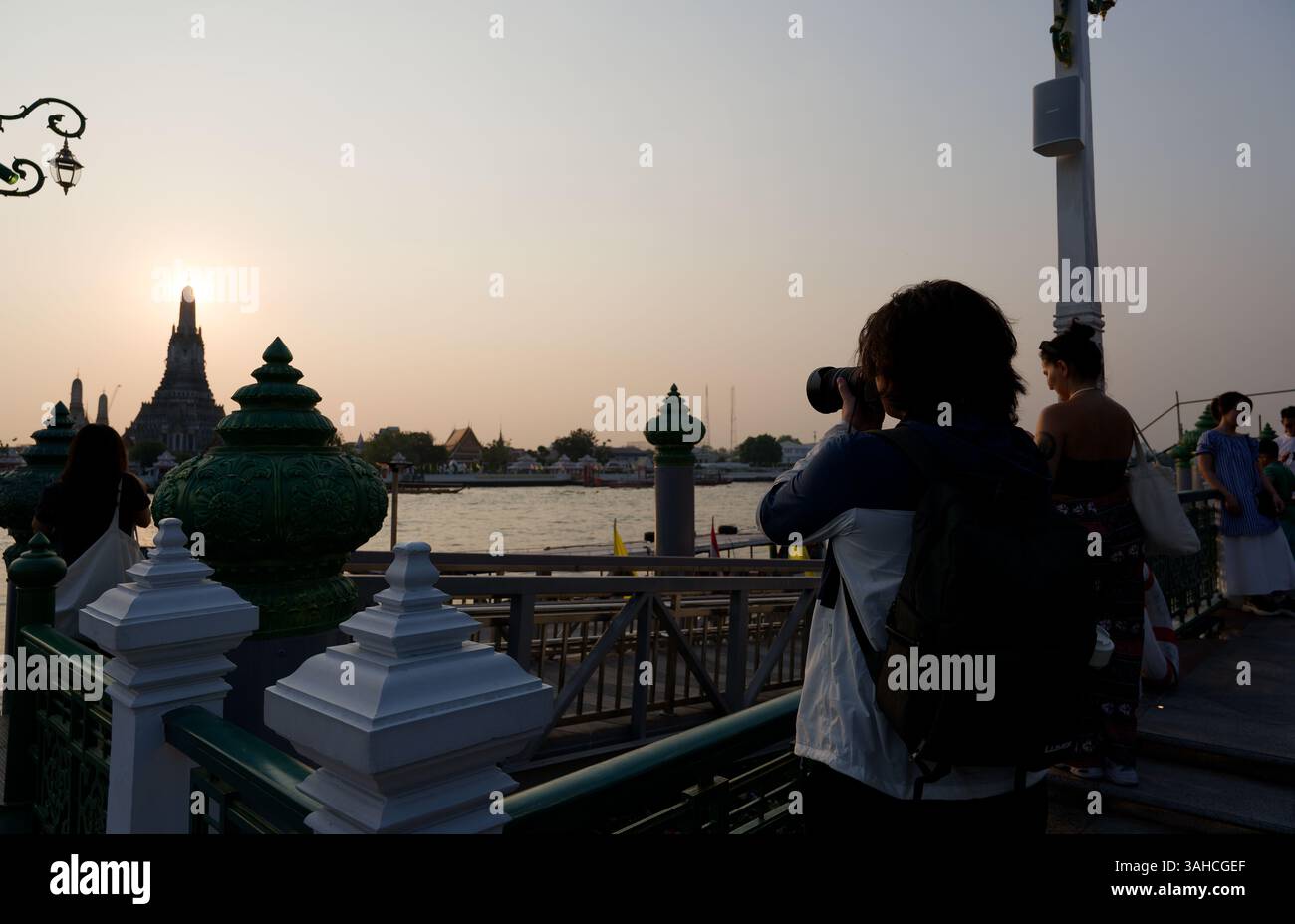 Il turista fotografa Wat Arun mentre il sole tramonta sul fiume Chao Phraya Foto Stock