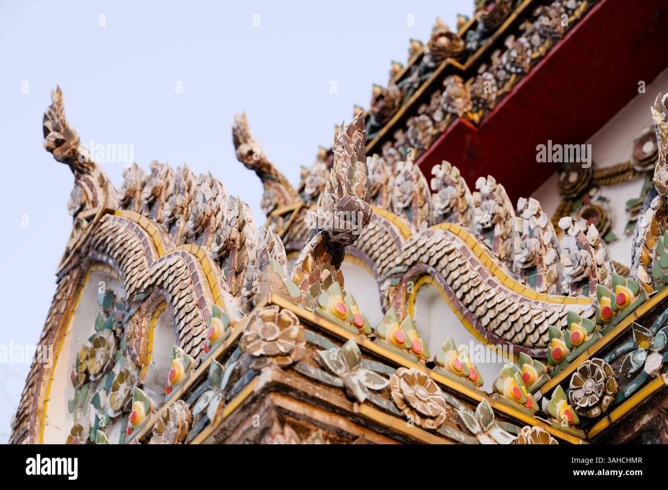Il tetto del tempio ornato di Wat Pho, che mostra motivi serpenti e intricati mosaici floreali Foto Stock
