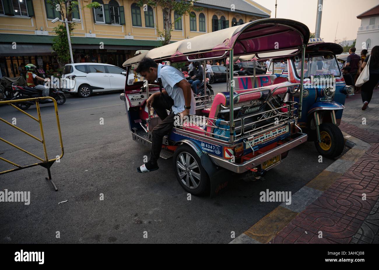 Un autista di tuk-tuk locale si allunga durante una pausa Foto Stock