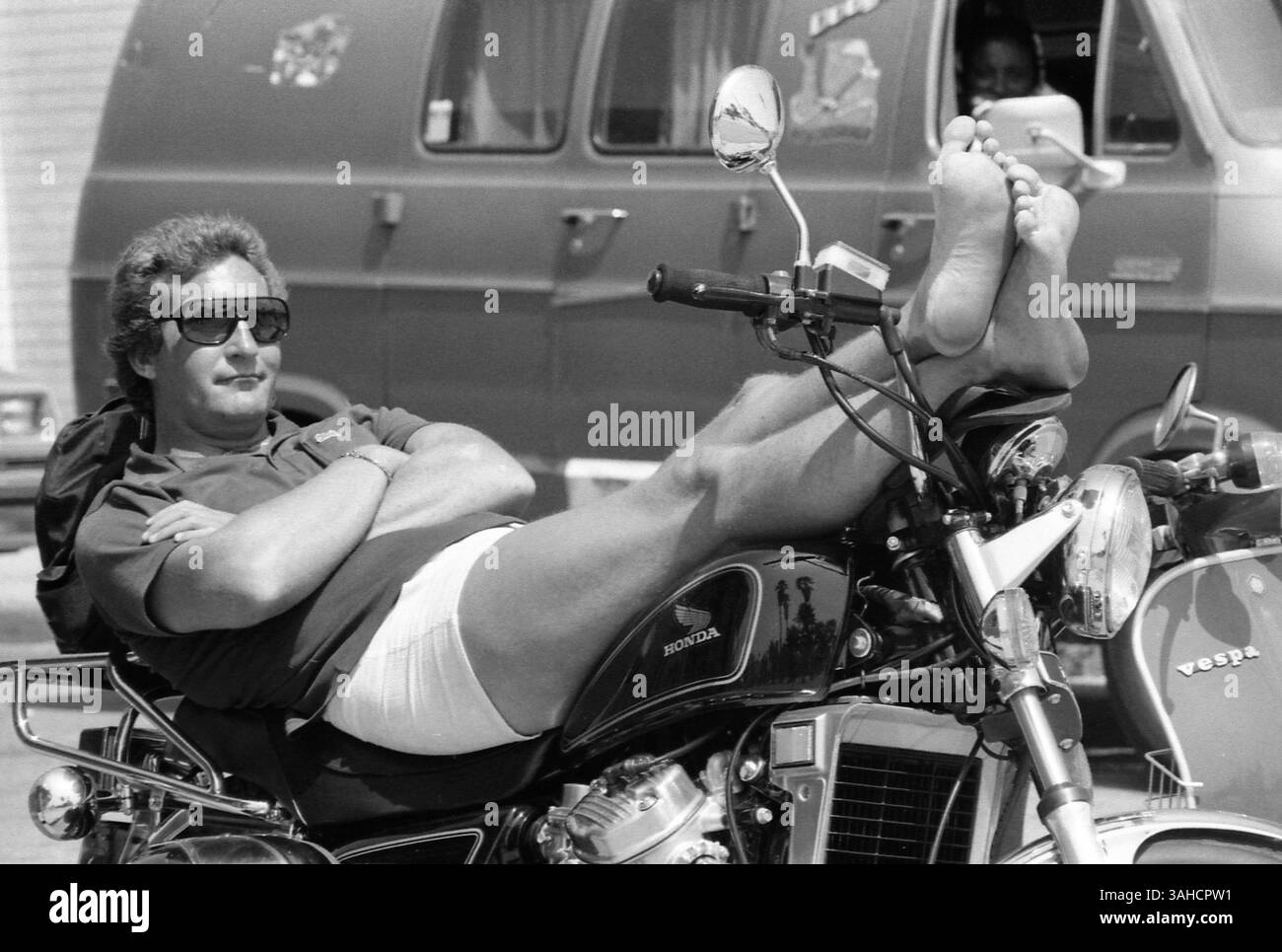 Los Angeles, CALIFORNIA, USA, circa 1985. Foto sincera di un uomo che si rilassa sulla sua moto parcheggiata. Foto Stock