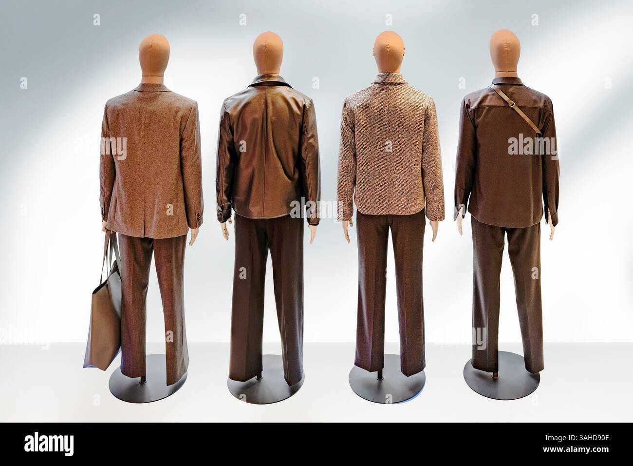 Gruppo di quattro manichini maschili che indossano abiti alla moda, rivolti lontano dallo spettatore. Sfondo bianco, tracciato di ritaglio. Foto Stock