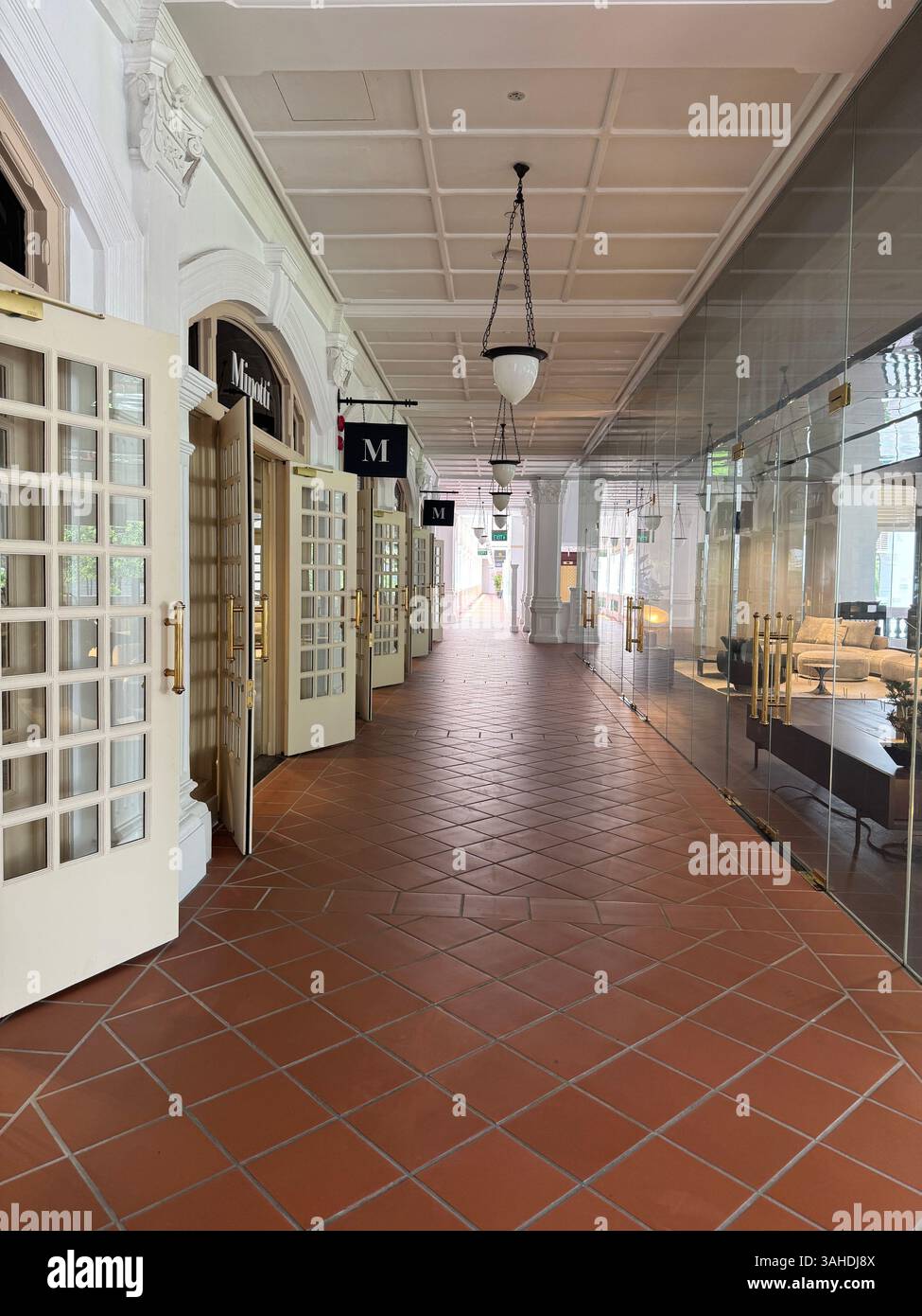 Corridoio coloniale bianco con porte aperte al Raffles Hotel, Singapore. Elegante architettura storica in un ambiente storico di lusso. - Immagine stock catturata con smartphone