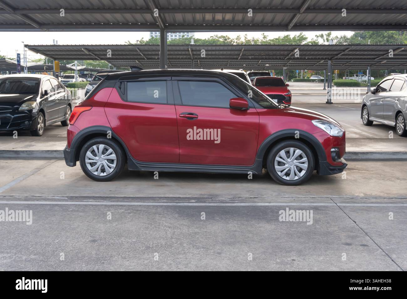 La vista sul lato destro della mini o piccola auto sportiva rossa con altre auto è il parcheggio all'aperto con il tetto di un grande magazzino. Foto Stock