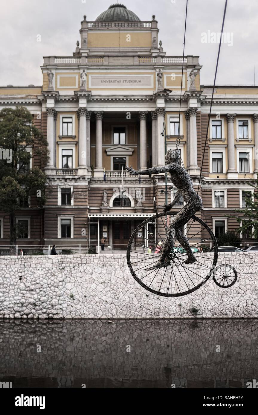 Scultura in filo metallico "The Cyclist" dall'installazione artistica "The Equilibrists" di Enes Sivac appesa di nuovo sul fiume Miljacka, su sfondo sfocato Foto Stock