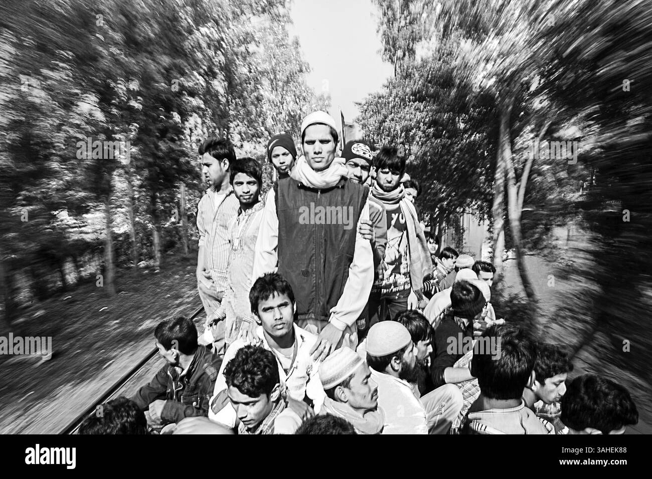 Le persone viaggiano sul tetto di un treno in rapido movimento in Bangladesh, mettendo in evidenza il sovraffollamento, il pericolo e la vita quotidiana dei pendolari poco serviti. Foto Stock