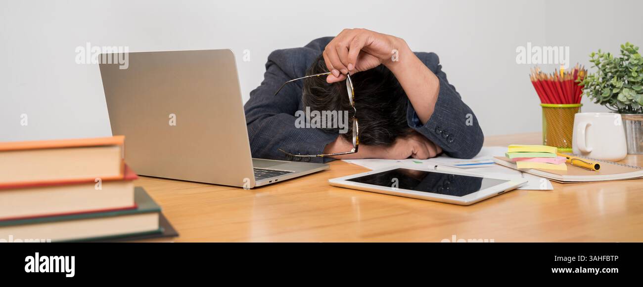 Un giovane lavoratore si è addormentato sul posto di lavoro in ufficio con la tastiera. Concetto di deprivazione del sonno e sovraccarico di lavoro. Tastiera stampata o Foto Stock