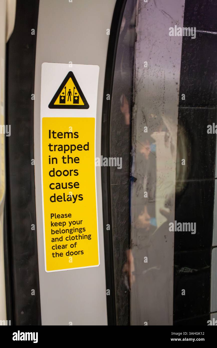 Un cartello sulla metropolitana di Londra avverte i passeggeri di fare attenzione a non far intrappolare i loro averi nelle porte della metropolitana. Inghilterra, Regno Unito Foto Stock