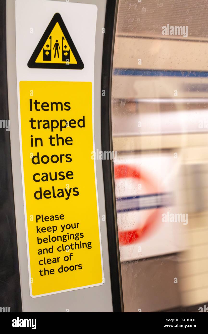 Un cartello sulla metropolitana di Londra avverte i passeggeri di fare attenzione a non far intrappolare i loro averi nelle porte della metropolitana. Inghilterra, Regno Unito Foto Stock