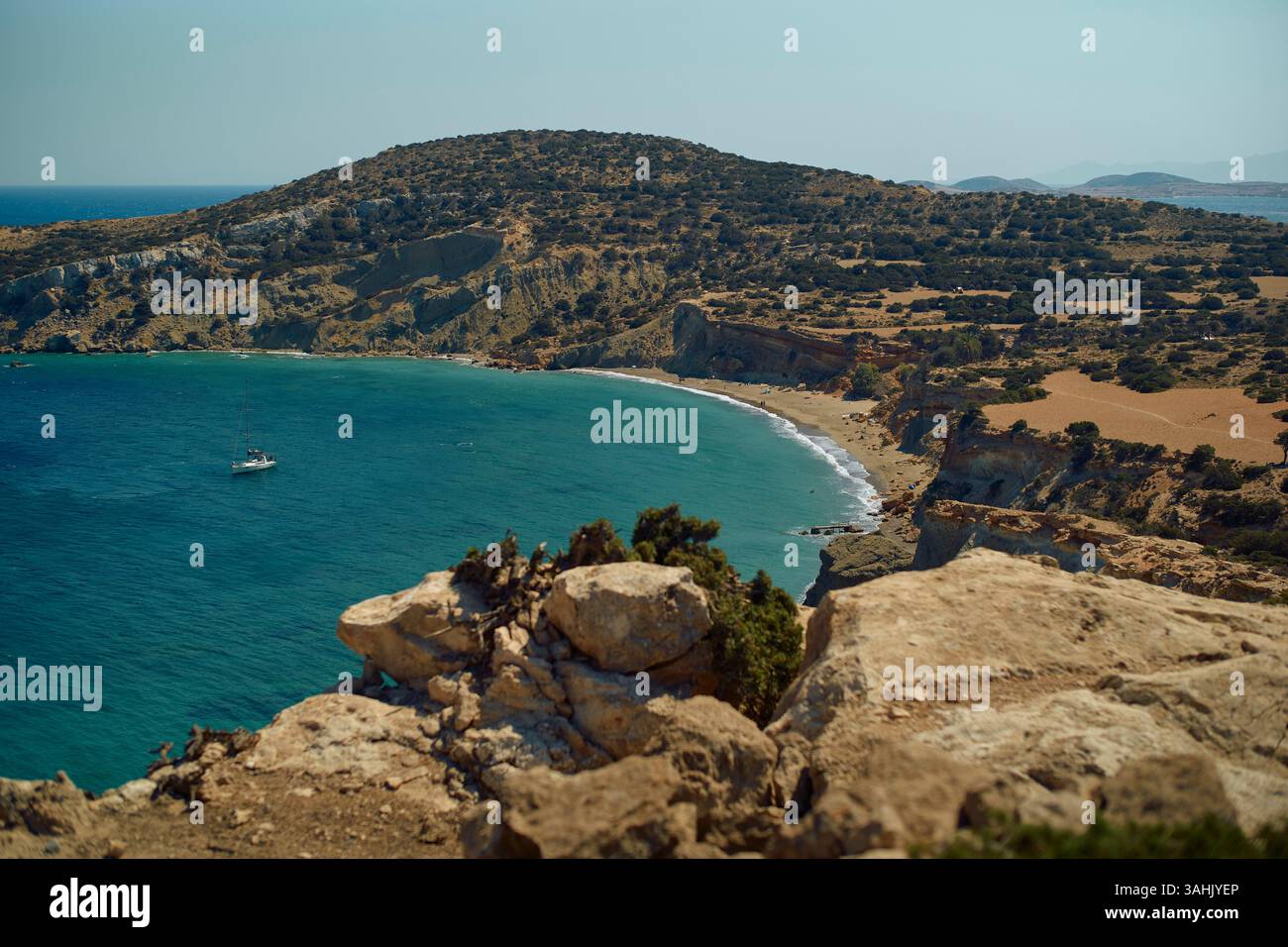 Paesaggio costiero panoramico con scogliere aspre, mare cristallino e una barca vicino al litorale. Mykonos, Grecia Foto Stock
