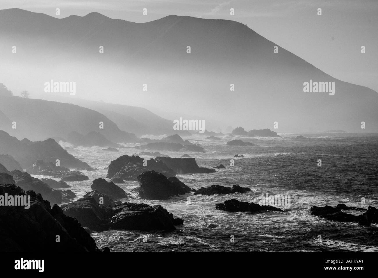 Costa montuosa con rocce aspre e onde che si infrangono in bianco e nero. Monterey, CALIFORNIA, Stati Uniti Foto Stock