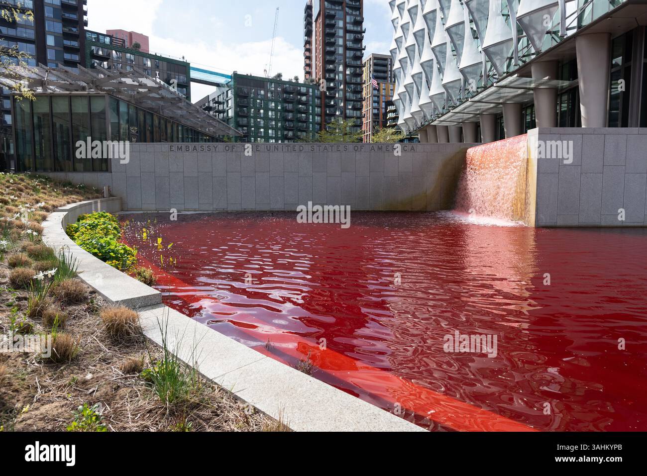 Londra, Regno Unito. 10 aprile 2025. Gli attivisti di Greenpeace tingono lo stagno che circonda l'ambasciata degli Stati Uniti a Nine Elms, Londra sangue rosso in una protesta contro il militarismo americano e il sostegno alla guerra di Israele a Gaza. Crediti: Ron Fassbender/Alamy Live News Foto Stock