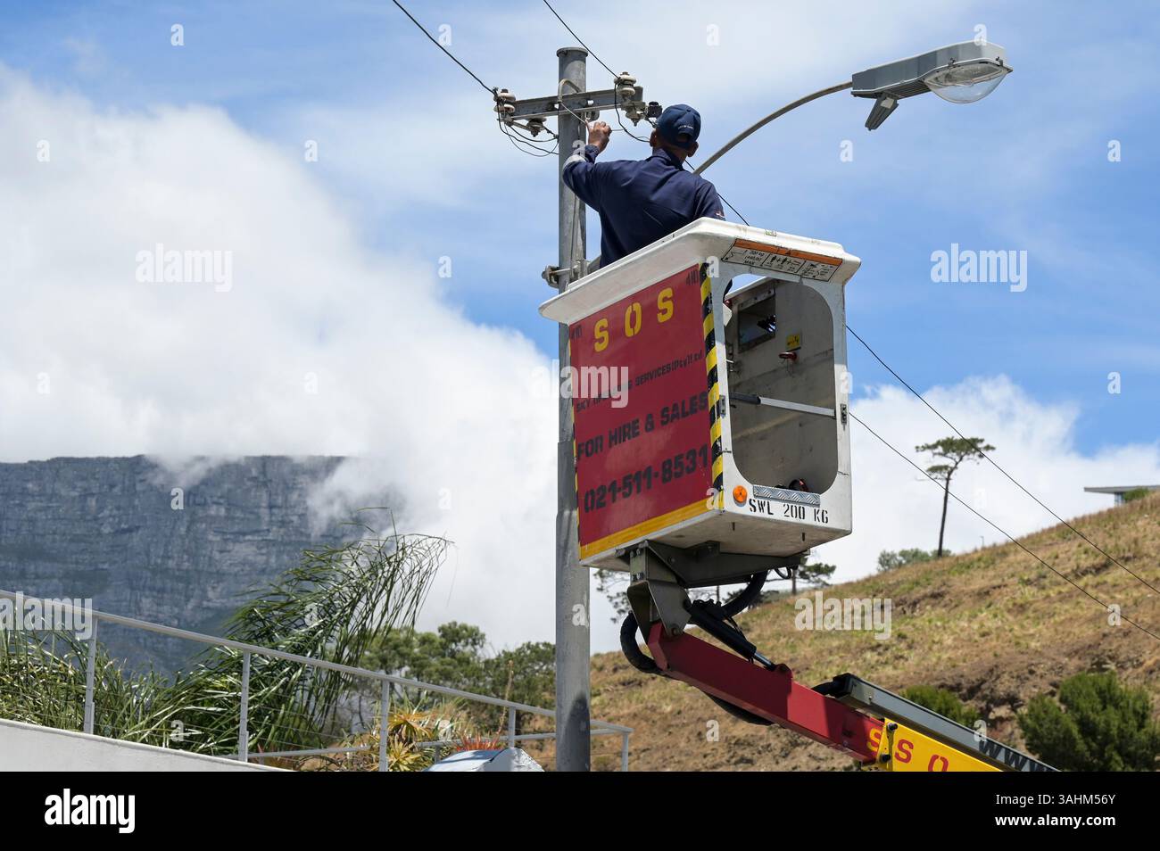 SUD AFRICA, città del Capo, alimentazione elettrica, addetto alla manutenzione, dietro la tavola di montagna / SÜDAFRIKA, Kapstadt, Stromversorgung, Elektriker, Hintergrund Tafelberg Foto Stock