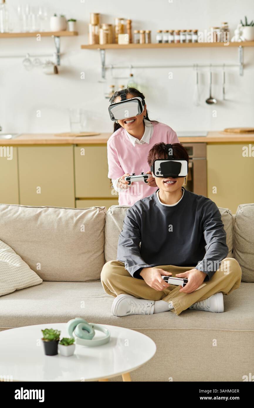 Una giovane coppia asiatica si impegna nel gioco virtuale a casa, condividendo risate ed emozioni. Foto Stock