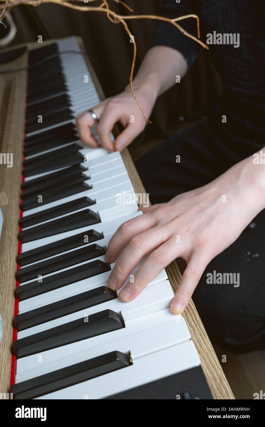 Un individuo di talento che suona abilmente un pianoforte indossando un elegante anello al dito, mostrando sia la loro arte che il loro stile Foto Stock