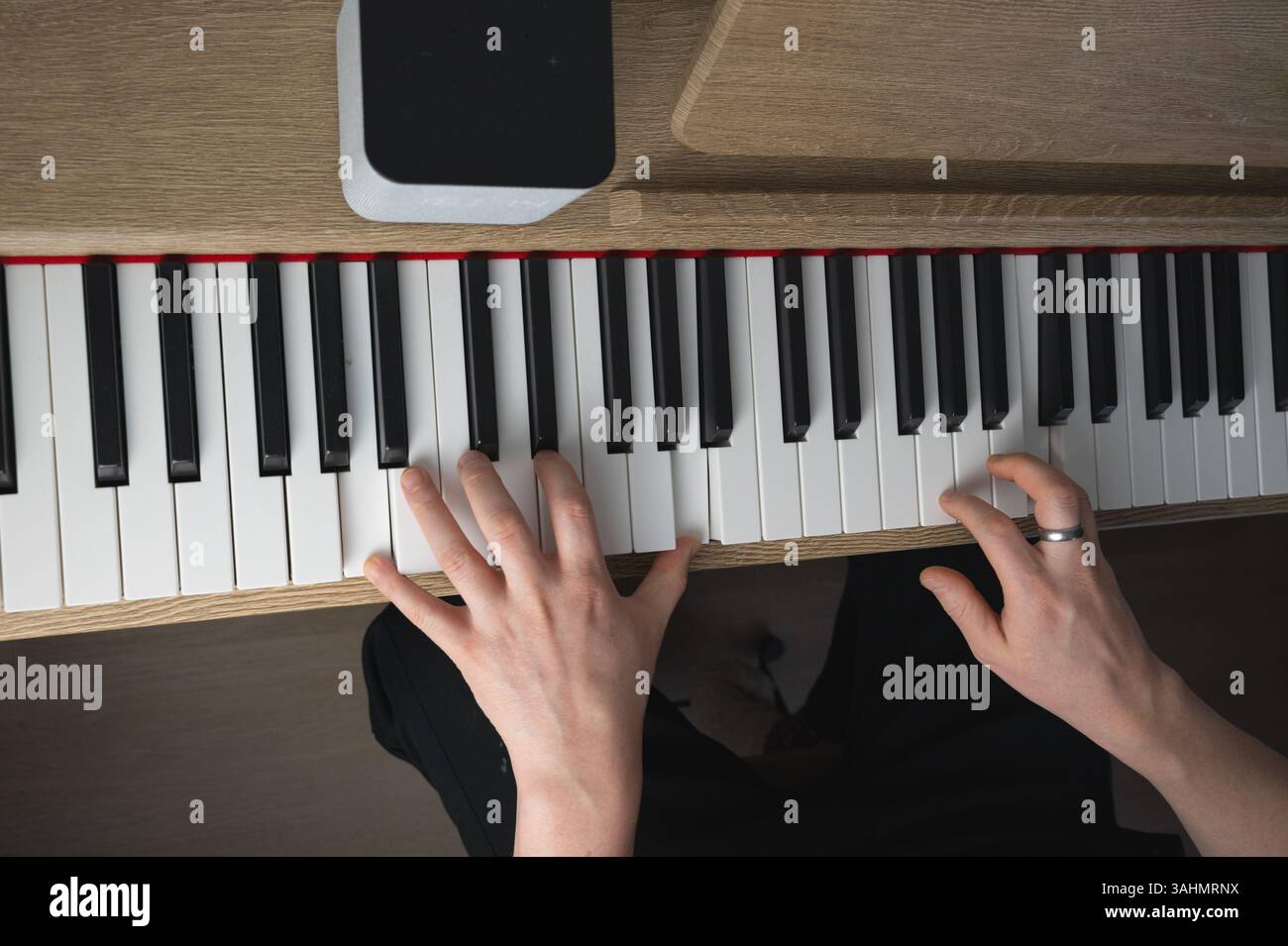 Un individuo sta suonando abilmente un pianoforte a coda, mostrando il suo talento indossando un bellissimo anello che adorna il dito Foto Stock