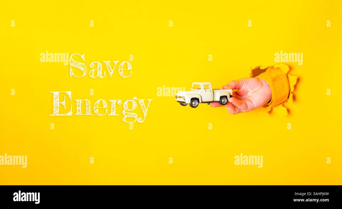 Tenere a mano un carrello giocattolo con le parole Save Energy (risparmio energia) riportate sotto di esso. Concetto di conservazione dell'energia e importanza di farlo. festa della terra c Foto Stock