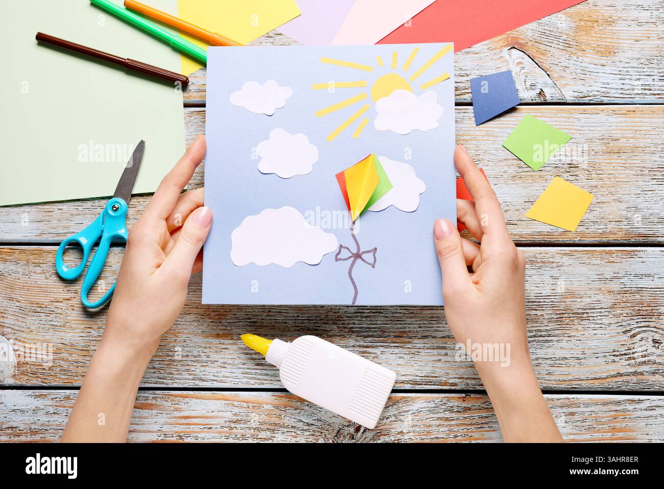 Donna con cartolina al tavolo di legno, vista dall'alto. Artigianato artigianale per bambini Foto Stock