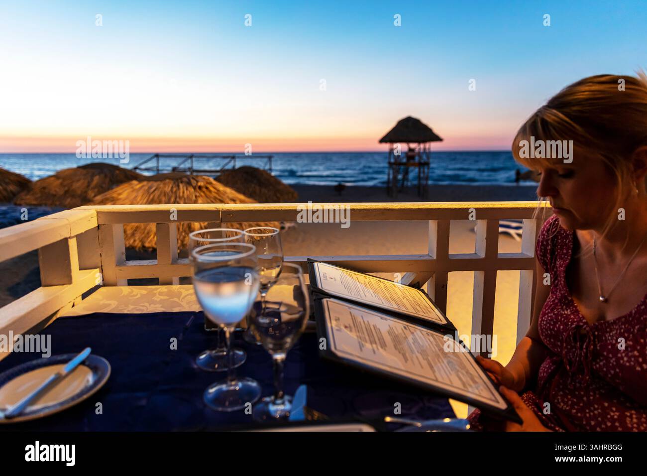 donna che legge menu, mangiare fuori di notte, leggere menu, ristorante sulla spiaggia, ristorante vista mare, vista mare, Varadero, Cuba, Repubblica di Cuba, Caraibi Foto Stock