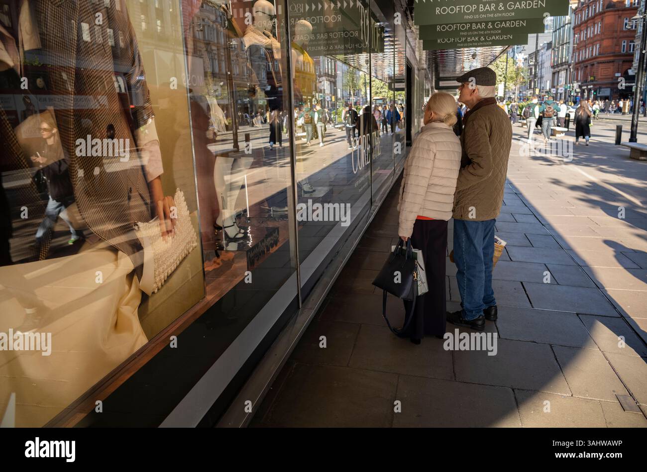 Coppia che guarda alla vetrina dei grandi magazzini John Lewis lungo la strada commerciale più trafficata di Londra, Oxford Street, West End, Inghilterra, Regno Unito Foto Stock