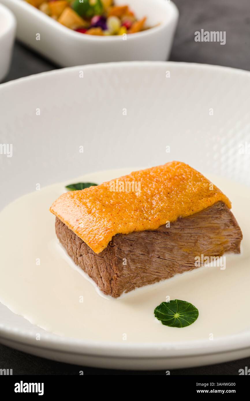 Manzo gourmet servito con salsa bianca cremosa e condimento croccante Foto Stock