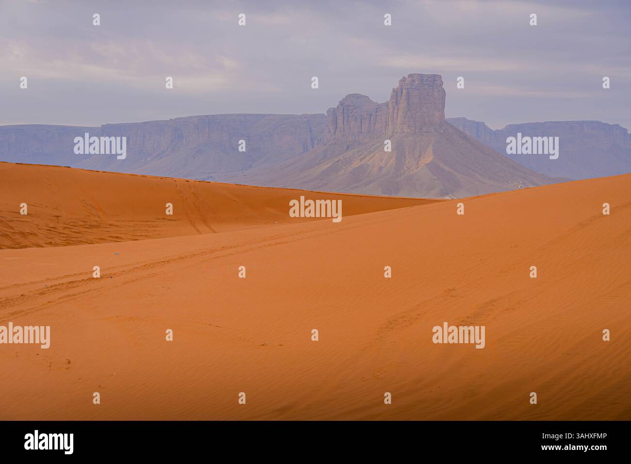 Splendida vista delle dune di sabbia rossa che incontrano formazioni rocciose uniche vicino a Riyad, Arabia Saudita, sotto un cielo morbido e silenzioso. Foto Stock