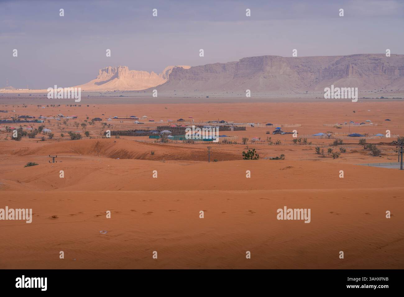 Ampia vista di un remoto villaggio desertico nella penisola arabica, l'Arabia Saudita, annidato tra sabbia e splendide formazioni rocciose. Foto Stock