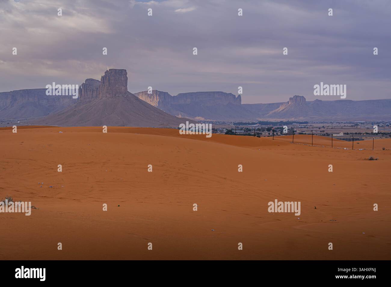 Ampia vista di un remoto villaggio desertico nella penisola arabica, l'Arabia Saudita, annidato tra sabbia e splendide formazioni rocciose. Foto Stock