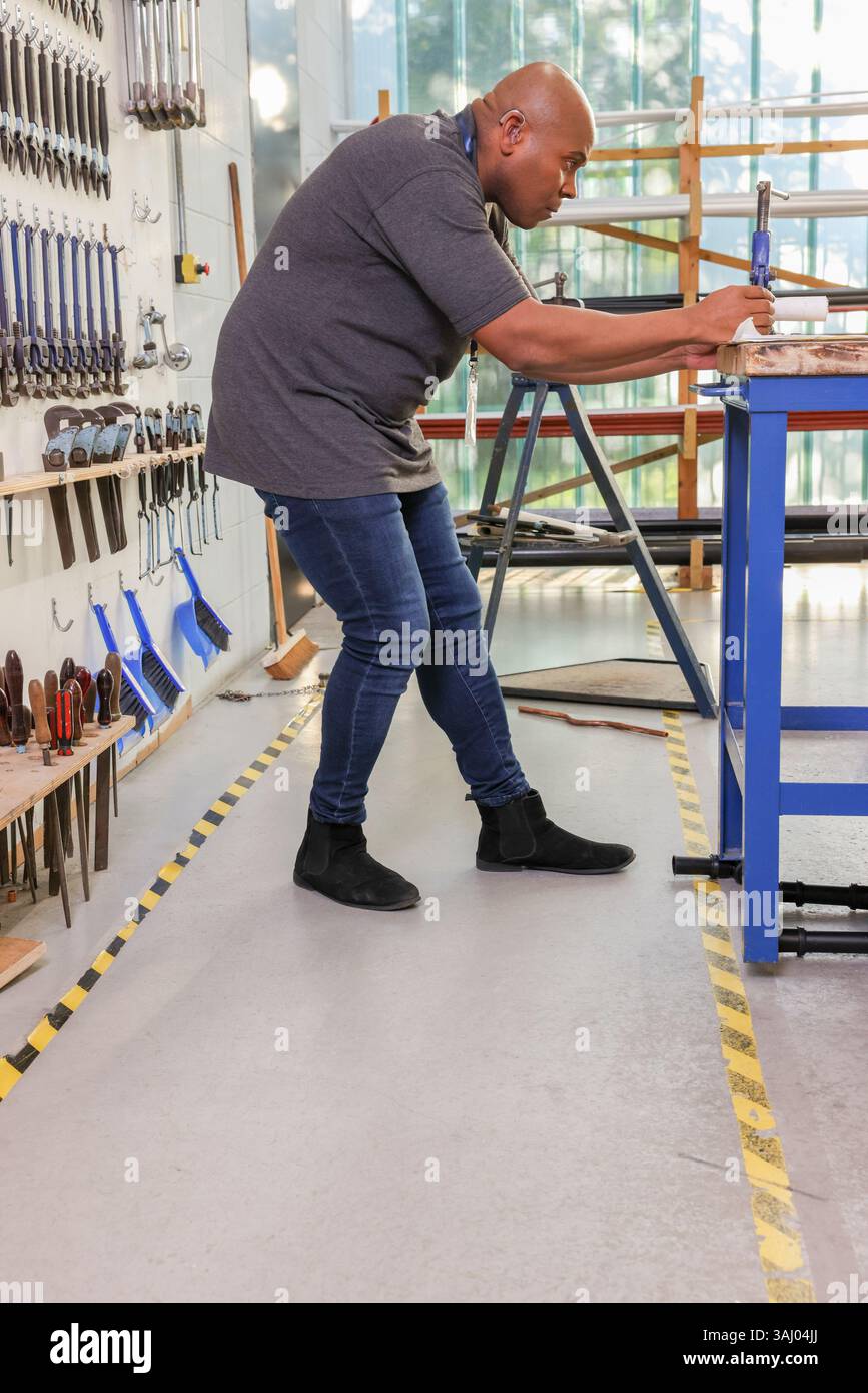 Uomo disabile che lavora in officina Foto Stock