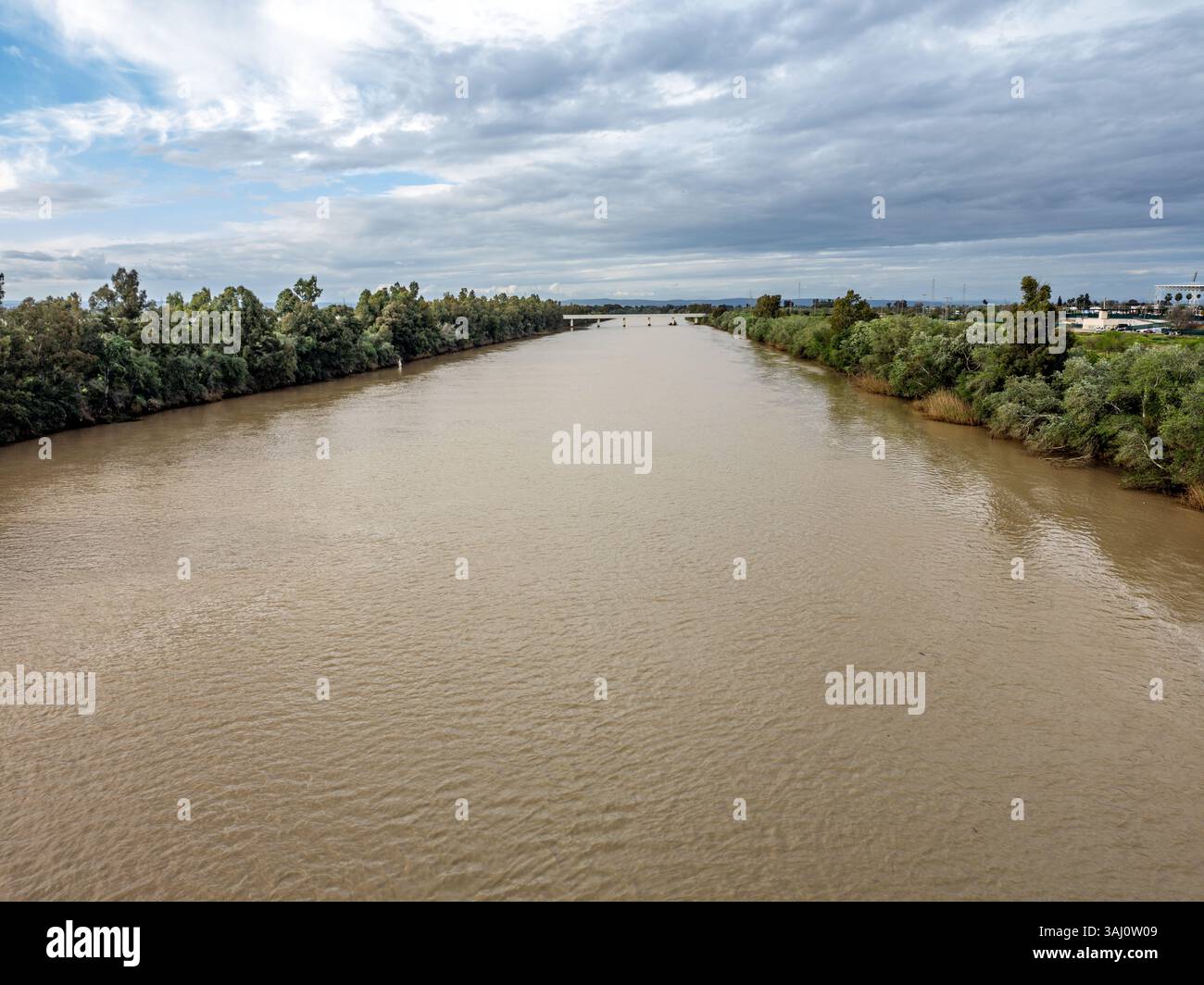 Le forti piogge inondano il fiume Guadalquivir vicino all'isola di Cartuja, mostrando la potenza della natura e i recenti cambiamenti climatici. Foto Stock
