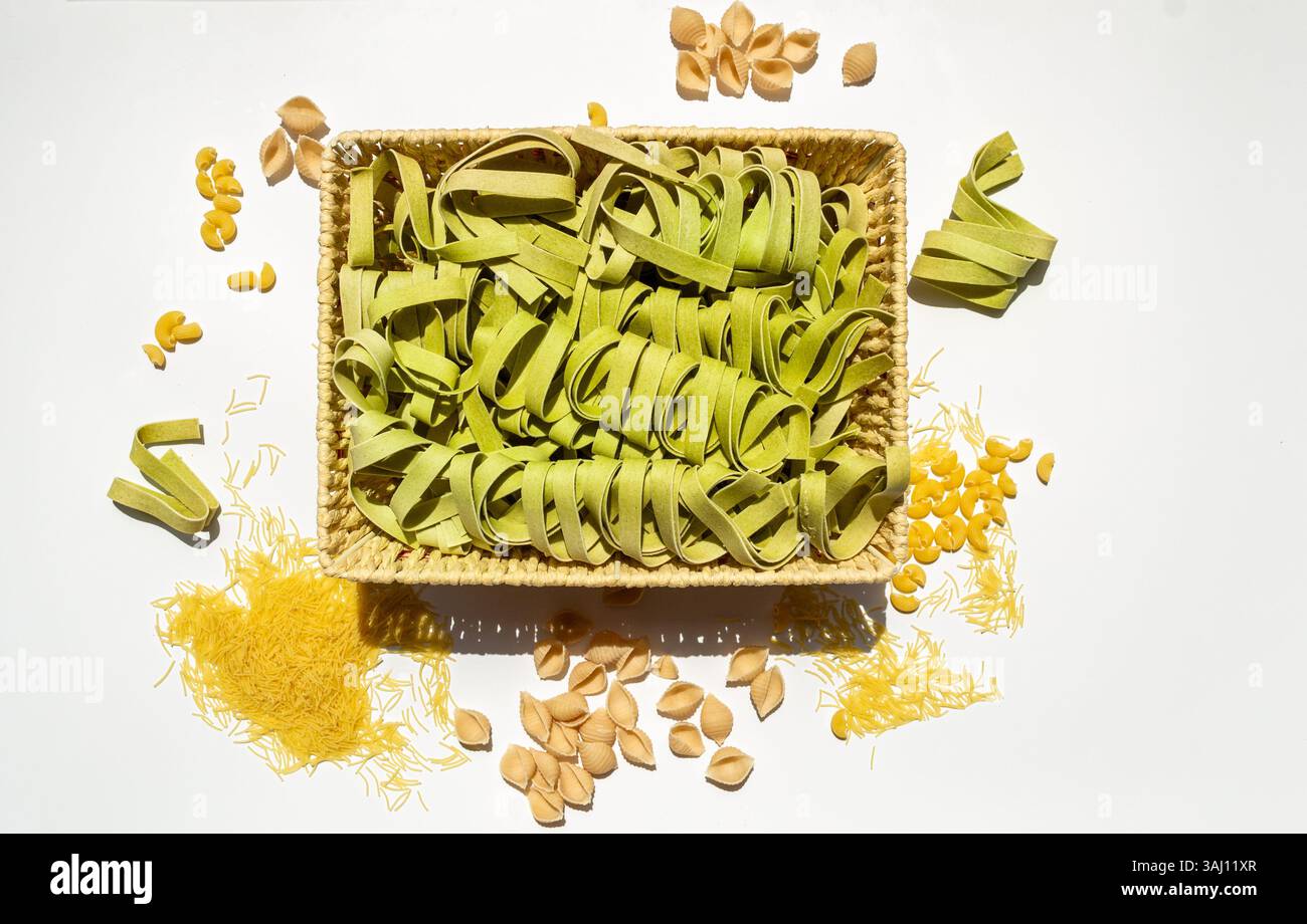 Tagliatelle di spinaci e pasta cruda assortita su sfondo bianco Foto Stock
