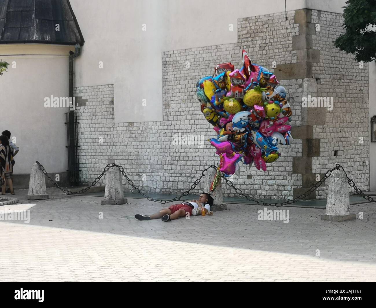 Venditore di mongolfiere che lottava nel caldo estivo di Cracovia in Polonia e che si faceva uno snooze sfacciato. - Immagine stock catturata con smartphone