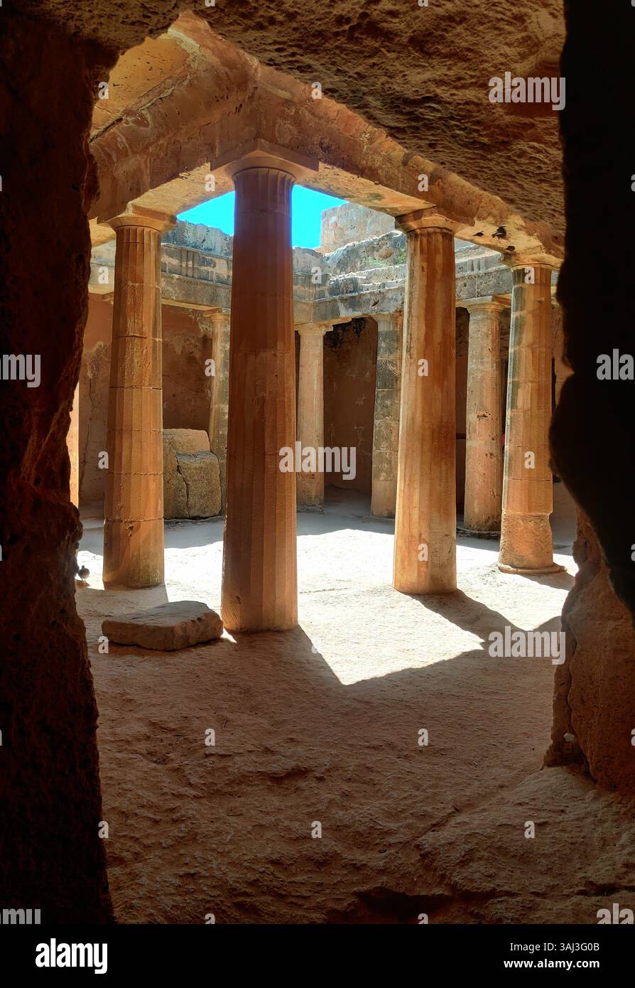 All'interno della Tomba dei Re, Paphos, colonne di pietra illuminate dal sole custodiscono l'antico silenzio in questo maestoso sito di sepoltura scavato nella roccia di Cipro. Foto Stock