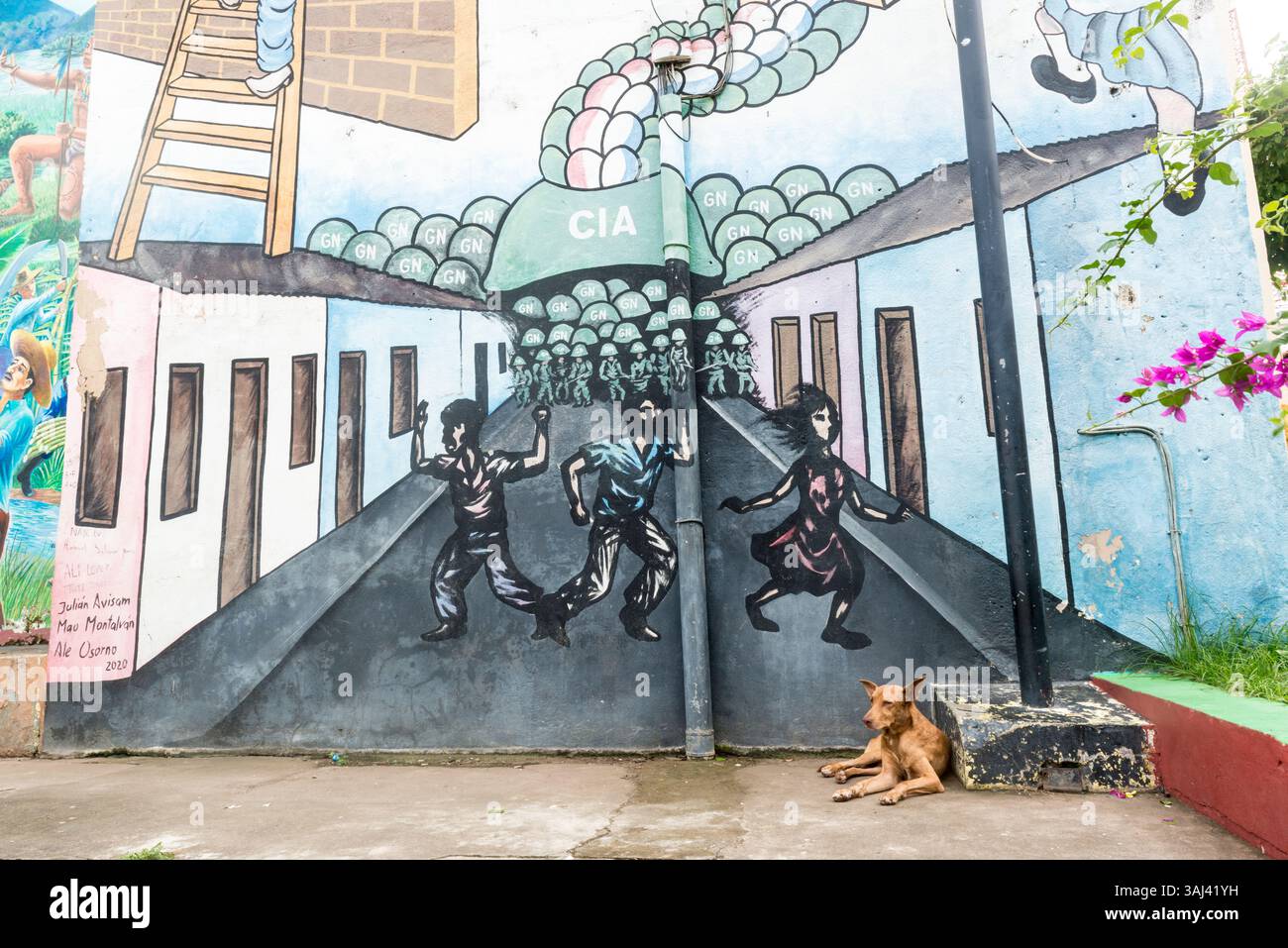 Un cane da strada marrone giace di fronte a un murale politico sull'oppressione del regime di Somoza sostenuto dagli Stati Uniti. Leon, Nicaragua. Foto Stock