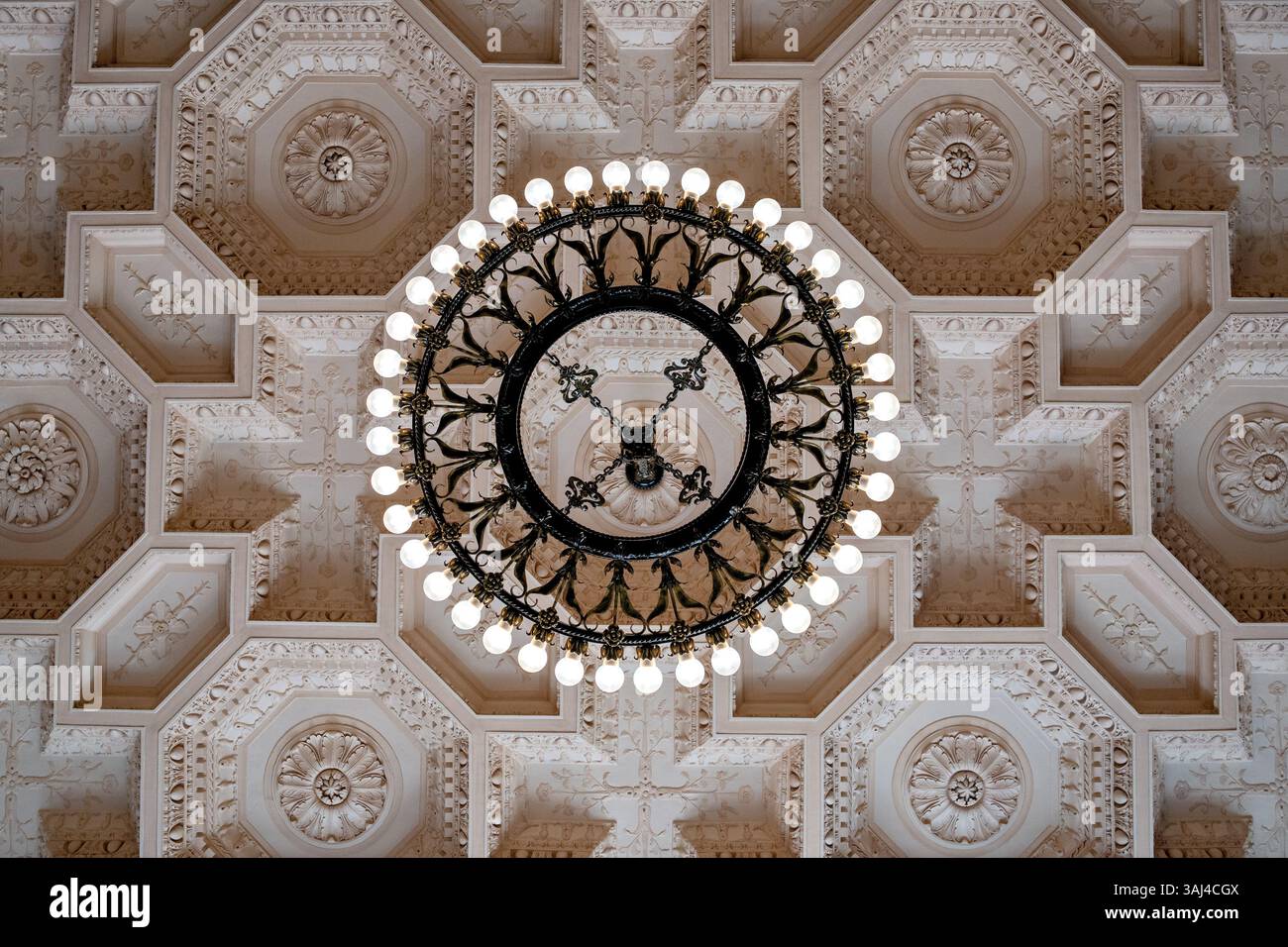 WASHINGTON DC - Un lampadario circolare in metallo appeso a un soffitto decorato in modo ornamentale nella sala d'ingresso dello Smithsonian National Museum of Asian Art's Freer Gallery. Questa elegante struttura architettonica esemplifica il design in stile rinascimentale italiano dell'edificio, creato dall'architetto Charles Platt e inaugurato nel 1923 come primo museo d'arte dello Smithsonian Institution. L'intricata decorazione del soffitto e i lavori in metallo riflettono l'estetica classica revival popolare nell'architettura istituzionale americana dei primi anni del XX secolo. Foto Stock