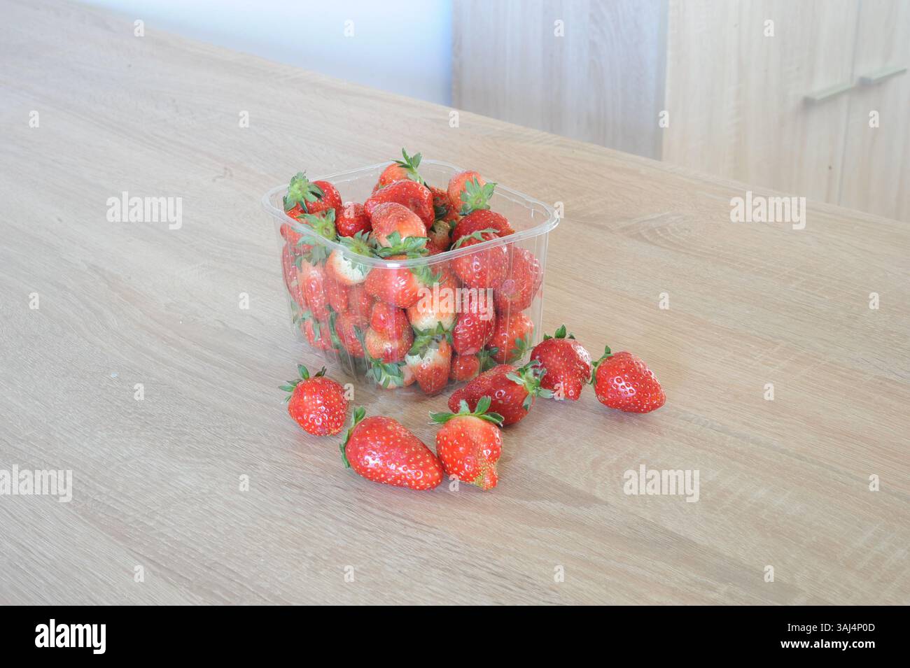 Fragole fresche dentro e fuori da una scatola su un tavolo Foto Stock