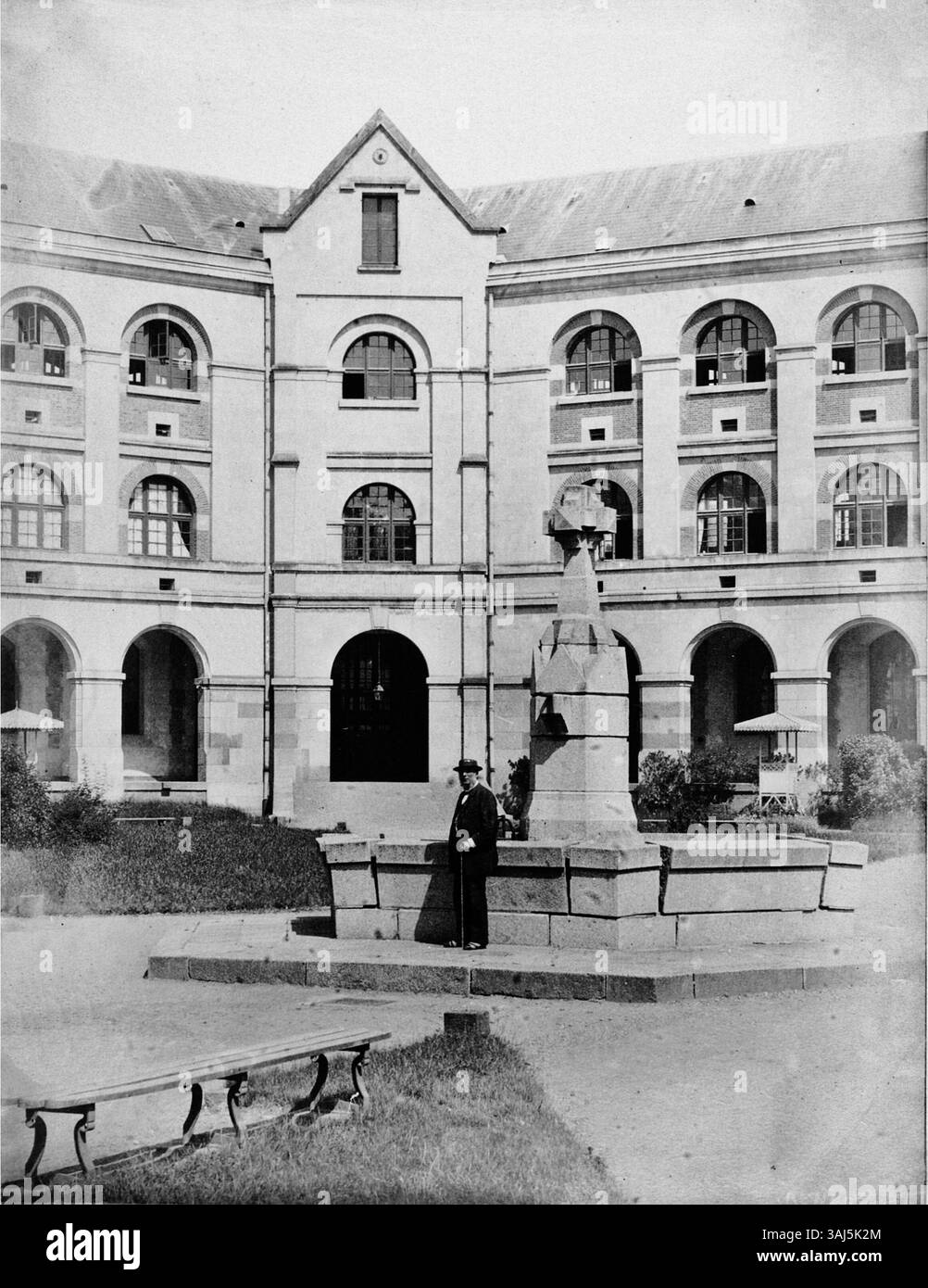 L'immagine mostra una vista della fontana nel cortile interno della Maison centrale pour femmes de Rennes, progettata da Alfred-Nicolas Normand. La fotografia è stata scattata intorno al 1865, evidenziando l'architettura della prigione e dei suoi dintorni. Foto Stock