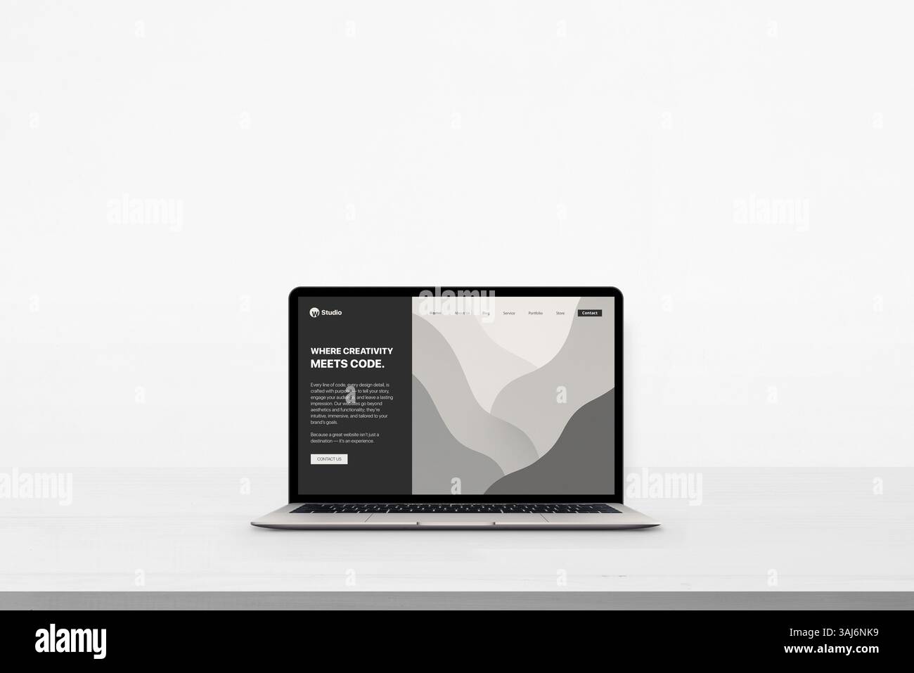 Laptop su una scrivania bianca e pulita con un sito Web concettuale minimalista che legge "dove la creatività incontra il codice", ideale per mostrare design e tecnologia Foto Stock