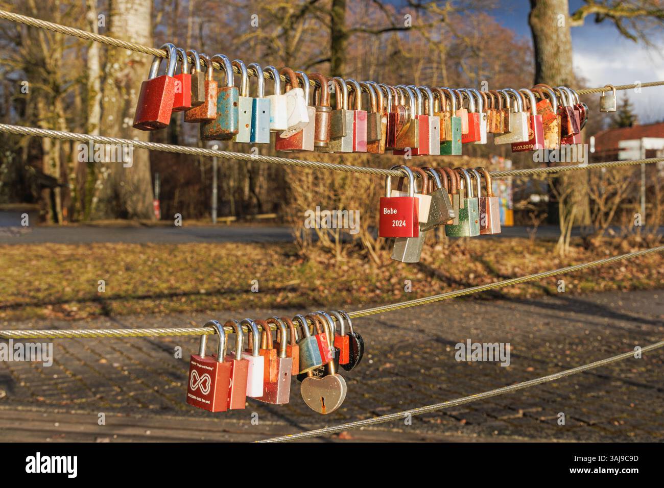 Serrature dell'amicizia, serrature dell'amore, numerose serrature colorate su funi metalliche di un piccolo ponte, Germania, Baviera, Lago Chiemsee, Seebruck Foto Stock