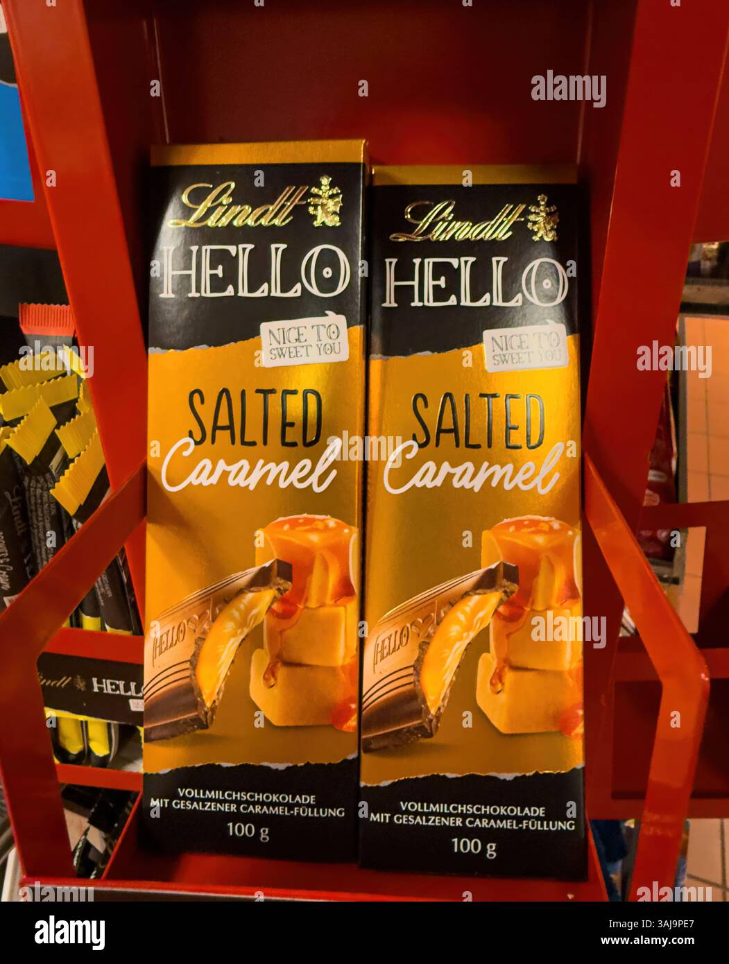 Due tavolette di cioccolato al caramello salato lindt hello si trovano su uno scaffale rosso, pronti per l'acquisto - FRANCOFORTE, GERMANIA - 9 APRILE 2025 Foto Stock